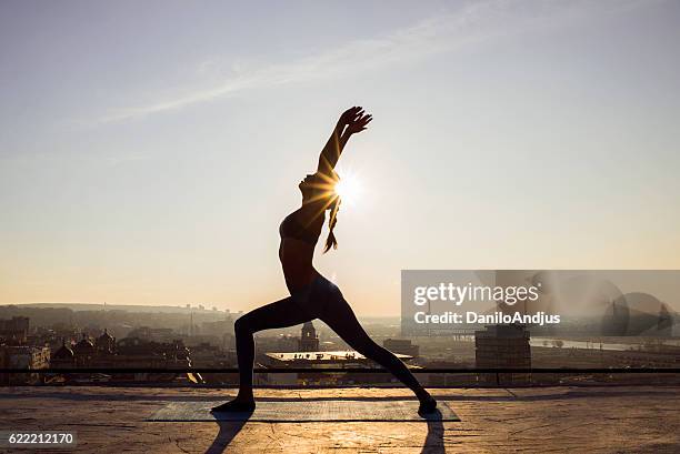 image of a woman doing yoga on a rooftop - rooftop yoga stock pictures, royalty-free photos & images