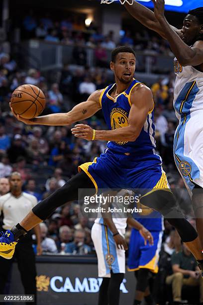 Golden State Warriors guard Stephen Curry flies under Denver Nuggets forward Kenneth Faried as he makes a pass from under the basket during the third...