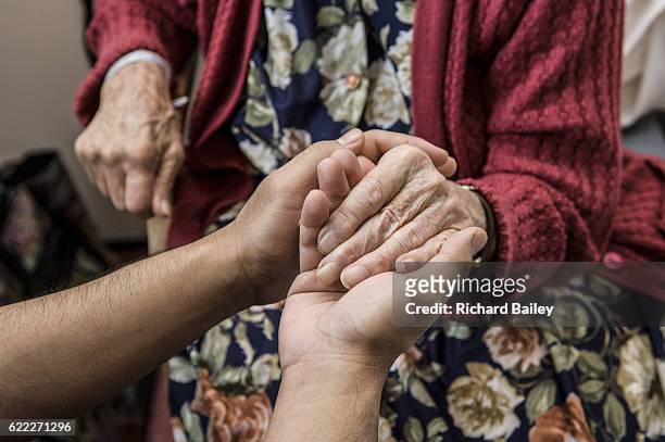 nurse holding hands with elderly patient. - humanidad fotografías e imágenes de stock