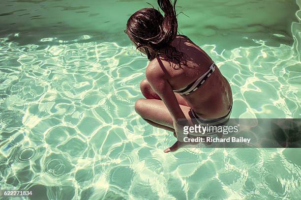 young girl dive bombing into swimming pool. - cannonball diving stock-fotos und bilder
