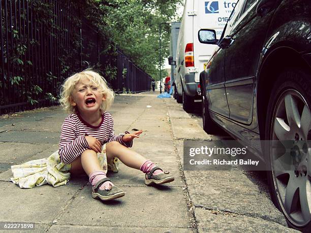 small girl having a tantrum on the pavement. - trotzanfall stock-fotos und bilder