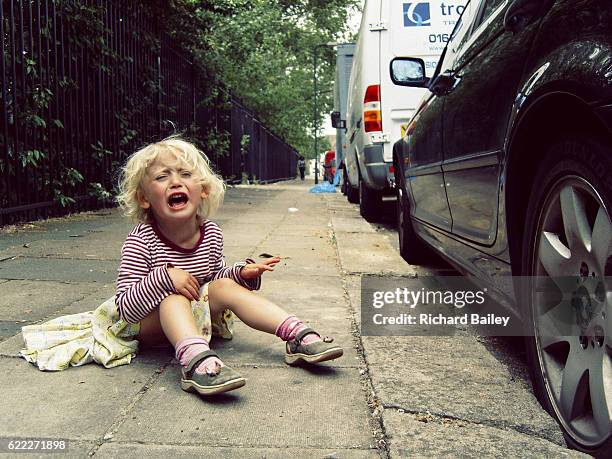 small girl having a tantrum on the pavement. - rage photos et images de collection