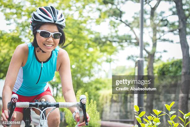 happy mid adult japanese woman riding bike in kyoto, japan - roupa desportiva de protecção imagens e fotografias de stock