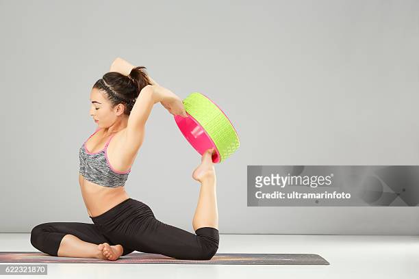 mujer practicando yoga avanzado pilates estiramiento entrenamiento yoga rueda poses - training wheels fotografías e imágenes de stock