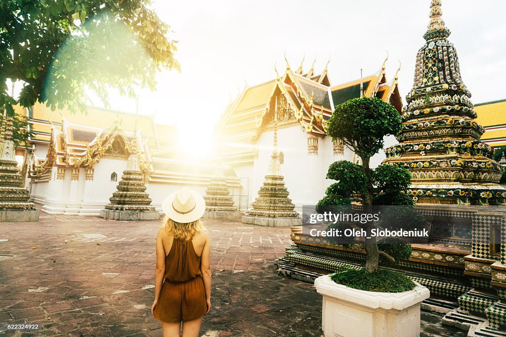 Woman walking in Wat Pho temple at sunrise