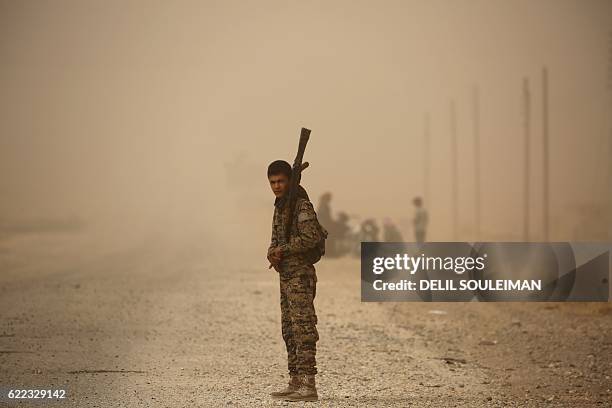 Member of the Syrian Democratic Forces , a US-backed Kurdish-Arab alliance, stands at attention during a sandstorm at a temporary refugee camp in the...