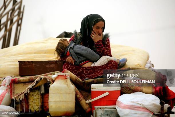 Syrian woman carries her child at a temporary refugee camp in the village of Ain Issa, housing people who fled Islamic State group's Syrian...