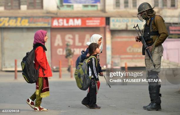 Kashmiri residents walk past Indian paramilitary troopers as they stand guard during curfew and restrictions in downtown Srinagar as the unrest in...