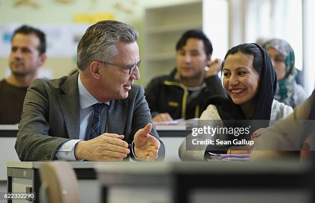 German Interior Minister Thomas de Maiziere sits next to Golale Nori, a young woman from Afghanistan who arrived in Germany with her husband and two...