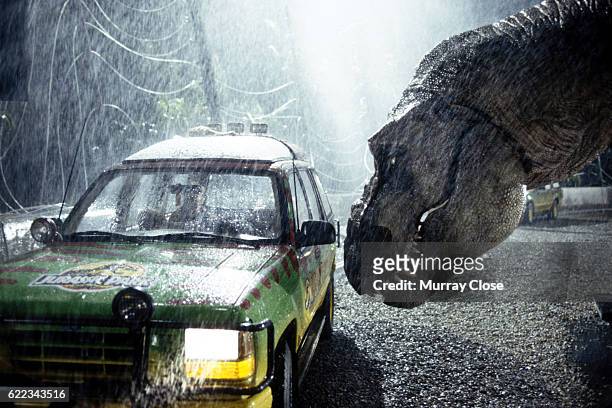 Tyrannosaurus rex terrorizes people trapped in a car in a scene from the 1993 American film Jurassic Park directed by Steven Spielberg. The sci-fi...