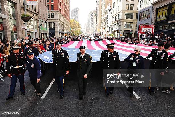 Veterans and others carry a large American Flag while marching in the nation's largest Veterans Day Parade in New York City on November 11, 2016 in...