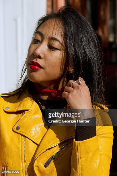 Tina Maria Tran with Urban Decay red lipstick wearing yellow pleather leather biker jacket with zips from Zara, black ribbed high neck top, Nick...
