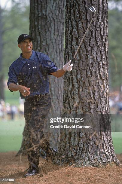 Tiger Woods of the USA follows his chip shot out of the rough between trees during The Masters at the Augusta National Golf Club in Augusta, Georgia....