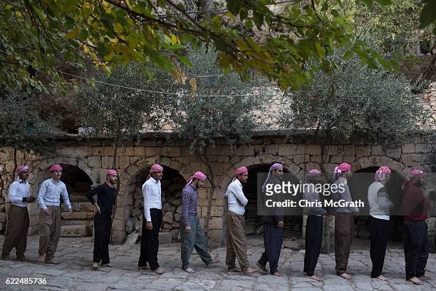 Yazidi men line up before starting a religious ritual outside the holiest temple of the Yazidi faith while attending friday rituals on November 11,...