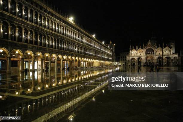 Tourists walk in the flooded St Mark's square during a night of acqua-alta or high-water in Venice, northern Italy, on November 11, 2016.