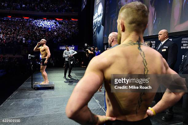 Lightweight champion Eddie Alvarez steps onto the scale as opponent Conor McGregor looks on during the UFC 205 weigh-in inside Madison Square Garden...