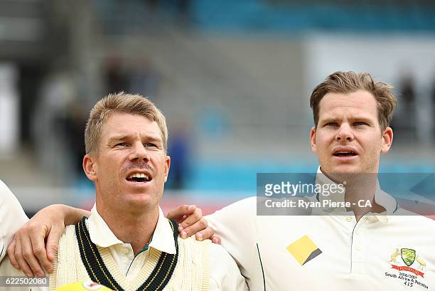 David Warner and Steve Smith of Australia sing the national anthem before their first teat match during day one of the Second Test match between...
