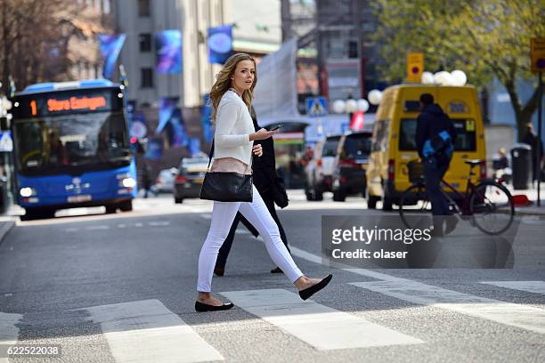 woman crossing street, zebra crossing, bus and traffic in background - pedestrian car stock pictures, royalty-free photos & images