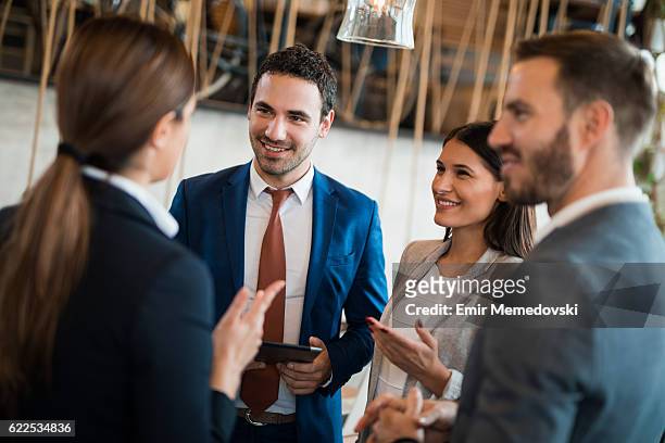 four business people discussing business strategy using digital tablet - business relationship stock pictures, royalty-free photos & images