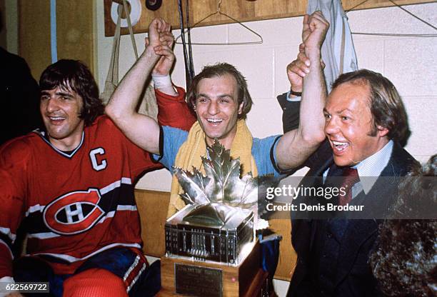 Serge Savard, Guy LaFleur, and Yvon Cournoyer of the Montreal Canadiens pose in locker room with the Conn Smythe Trophy awarded to LaFleur after...