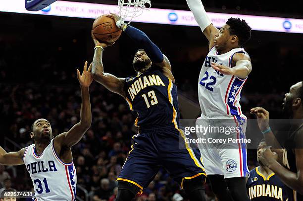 Paul George of the Indiana Pacers is guarded at the rim by Hollis Thompson and Richaun Holmes of the Philadelphia 76ers in the third quarter at the...