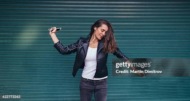 happy woman dancing to the music - girl in leather jacket stock pictures, royalty-free photos & images