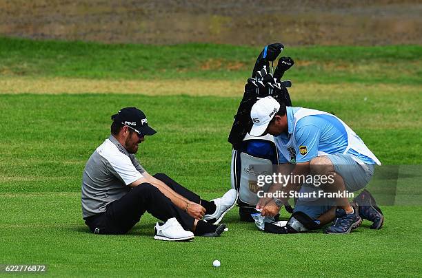 Louis Oosthuizen of South Africa gets some help for his blisters from his caddie during the third round of The Nedbank Golf Challenge at Gary Player...