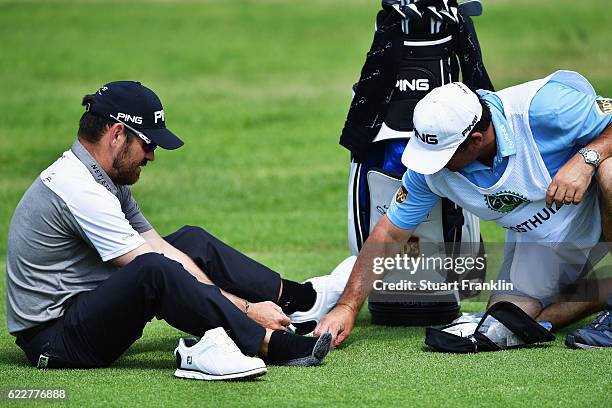 Louis Oosthuizen of South Africa gets some help for his blisters from his caddie during the third round of The Nedbank Golf Challenge at Gary Player...