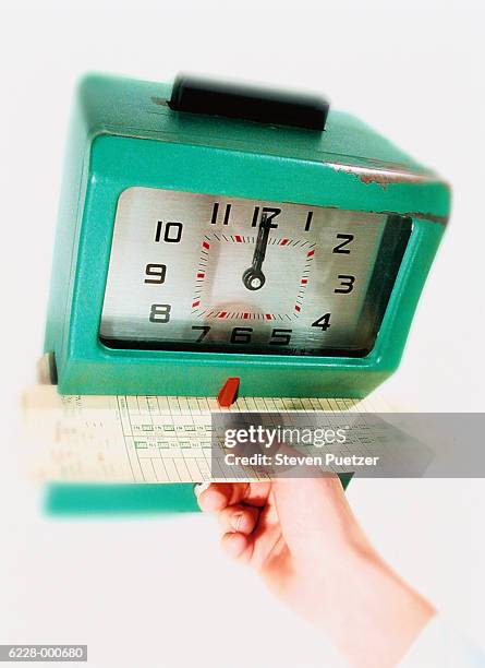 person puts time card in clock - stechkarte stock-fotos und bilder