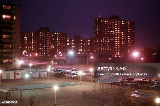 Streetlights illuminate a parking lot and sports fields in a park near a housing project in the Bronx, New York City, New York, 1974. .