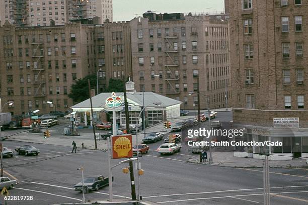 Cars pass through an intersection near Amoco and Shell gas stations, with the storefront of August and Zelkinson glass company visible, in the Bronx,...