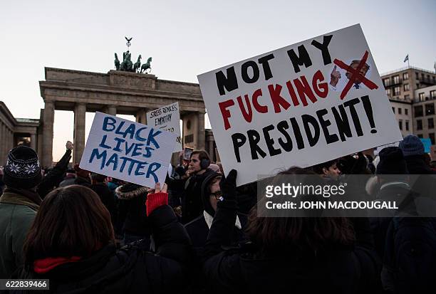 Demonstrator protesting against US president-elect Donald Trump displays a placard during a demonstration at Berlin's Brandenburg Gate on November...