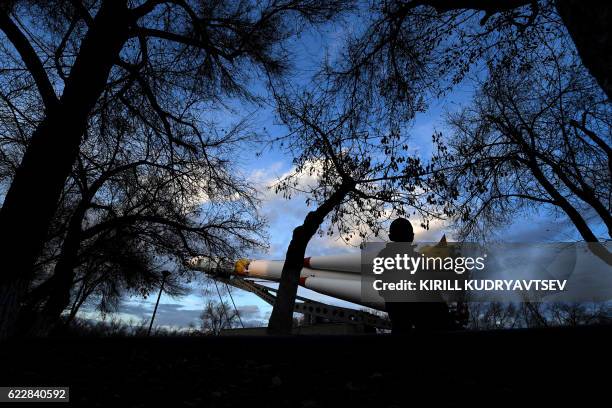 Kazakh boy walks past a Soyuz rocket installed as a monument in Baikonur near the well-known Russian-leased cosmodrome on November 12, 2016. French...