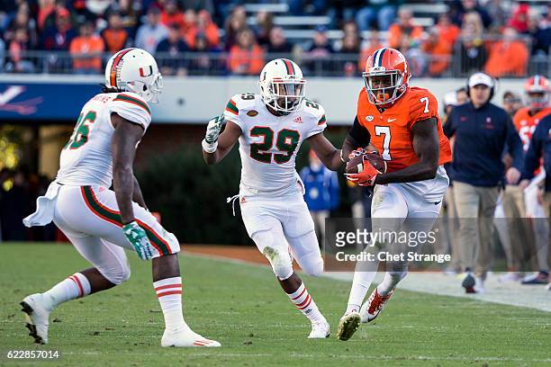 Doni Dowling of the Virginia Cavaliers runs the ball past Corn Elder of the Miami Hurricanes and Rayshawn Jenkins of the Miami Hurricanes during a...
