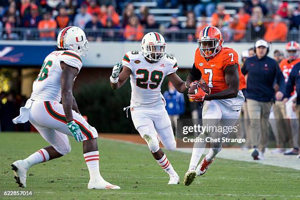 Doni Dowling of the Virginia Cavaliers runs the ball past Corn Elder of the Miami Hurricanes and Rayshawn Jenkins of the Miami Hurricanes during a...