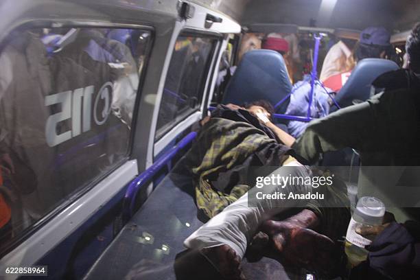 Pakistani rescue workers and volunteers unload an injured victim of bomb blast, from an ambulance upon his arrival at a local hospital in Hub town...