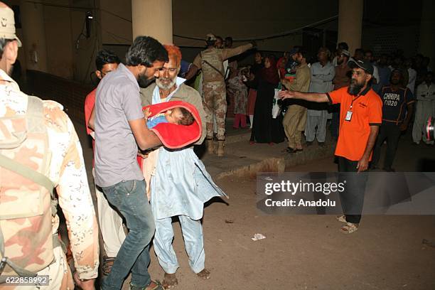 Pakistani rescue workers and volunteers unload an injured victim of bomb blast, from an ambulance upon his arrival at a local hospital in Hub town...