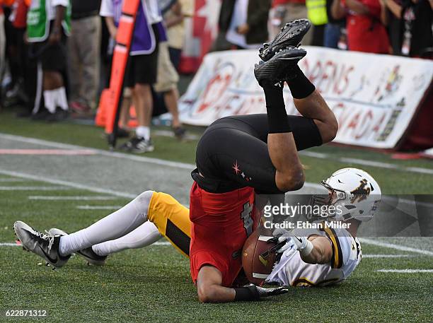 Defensive back Torry McTyer of the UNLV Rebels intercepts the ball in the third overtime against wide receiver Jake Maulhardt of the Wyoming Cowboys...