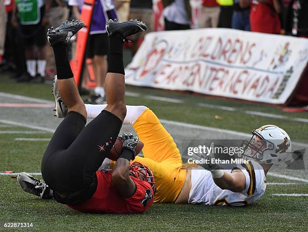 Defensive back Torry McTyer of the UNLV Rebels intercepts the ball in the third overtime against wide receiver Jake Maulhardt of the Wyoming Cowboys...