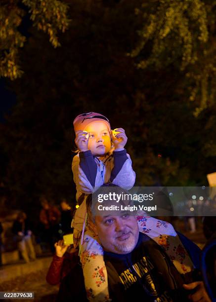 Falls Church, VA resident Jeff Keas carries his five-year old daughter Juliana Keas on his shoulders during a protest against election results next...