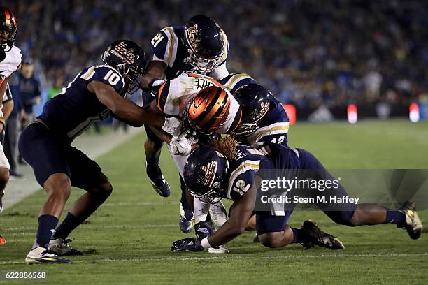 Tahaan Goodman, Fabian Moreau, Jayon Brown, and Kenny Young of the UCLA Bruins tackle Artavis Pierce of the Oregon State Beavers during the first...