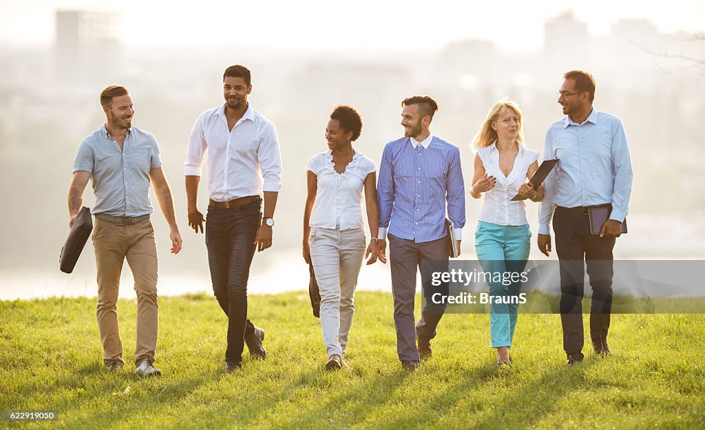 Smiling business colleagues communicating while taking a walk in nature.