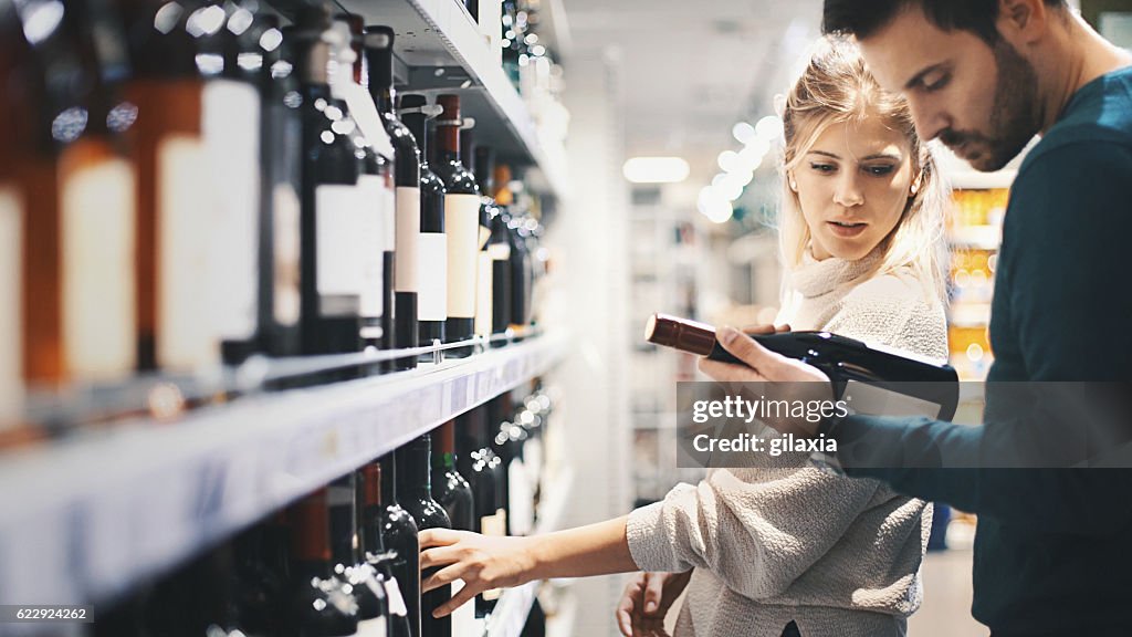 Couple buying some wine at a supermarket.