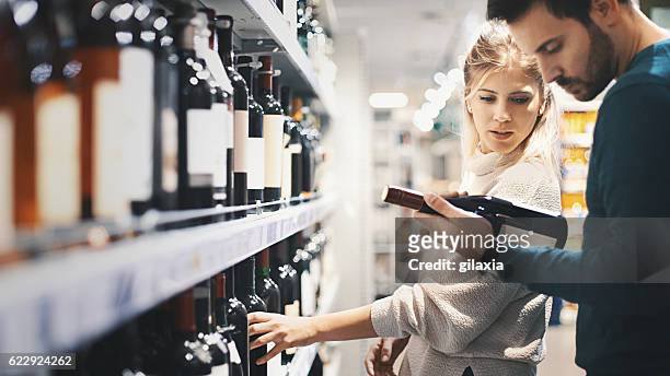 couple buying some wine at a supermarket. - bebida alcoólica imagens e fotografias de stock