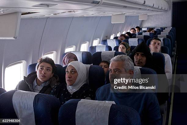 Syrian refugees; Hassan Asaaid Alkhateb, Mohamed and Lama watch a screen displaying their plane's route after boarding a special charter flight for...