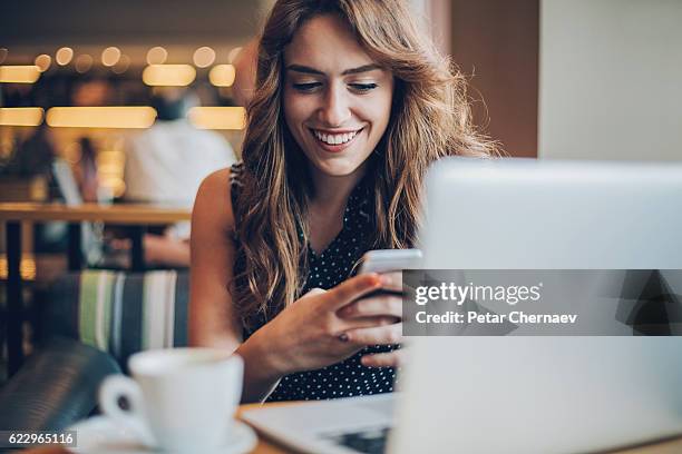 smiling girl texting in cafe - coffee chat stockfoto's en -beelden