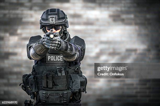 swat police officer against brick wall - police camera stockfoto's en -beelden