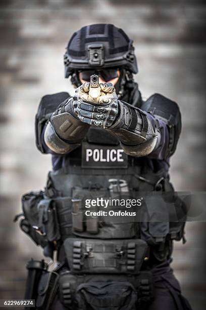 swat polizist gegen ziegelmauer - leuchtgeschoss stock-fotos und bilder