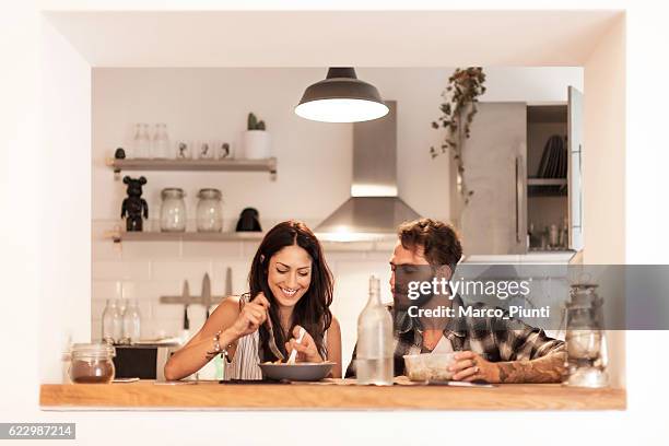 young couple eating together at home - contemporary couple stock pictures, royalty-free photos & images