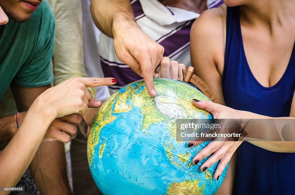 Teenagers searching place on a globe